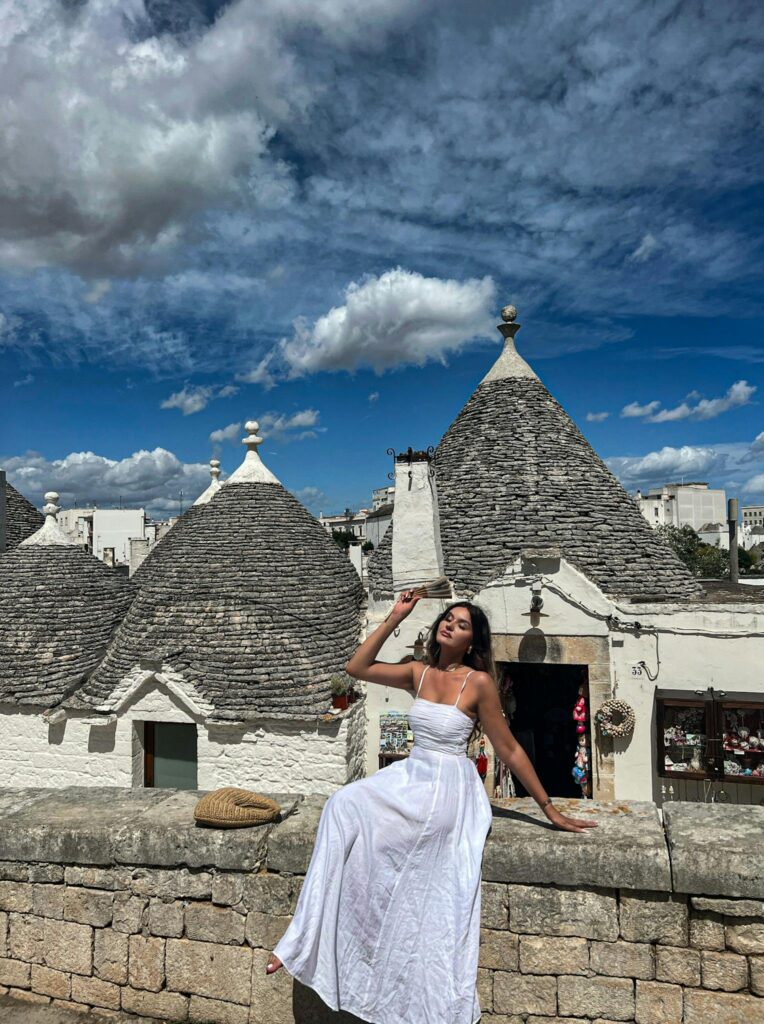 Woman Posing on Wall by Trulli Houses in Alberobello