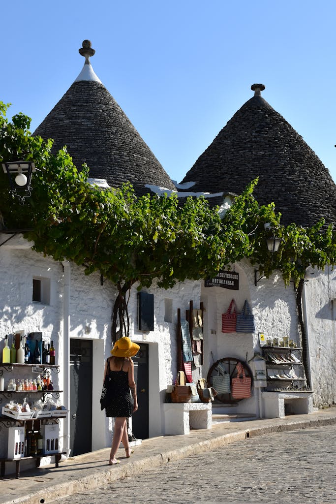 Charming view of historic Trulli houses in Alberobello, Italy, with a tourist exploring.