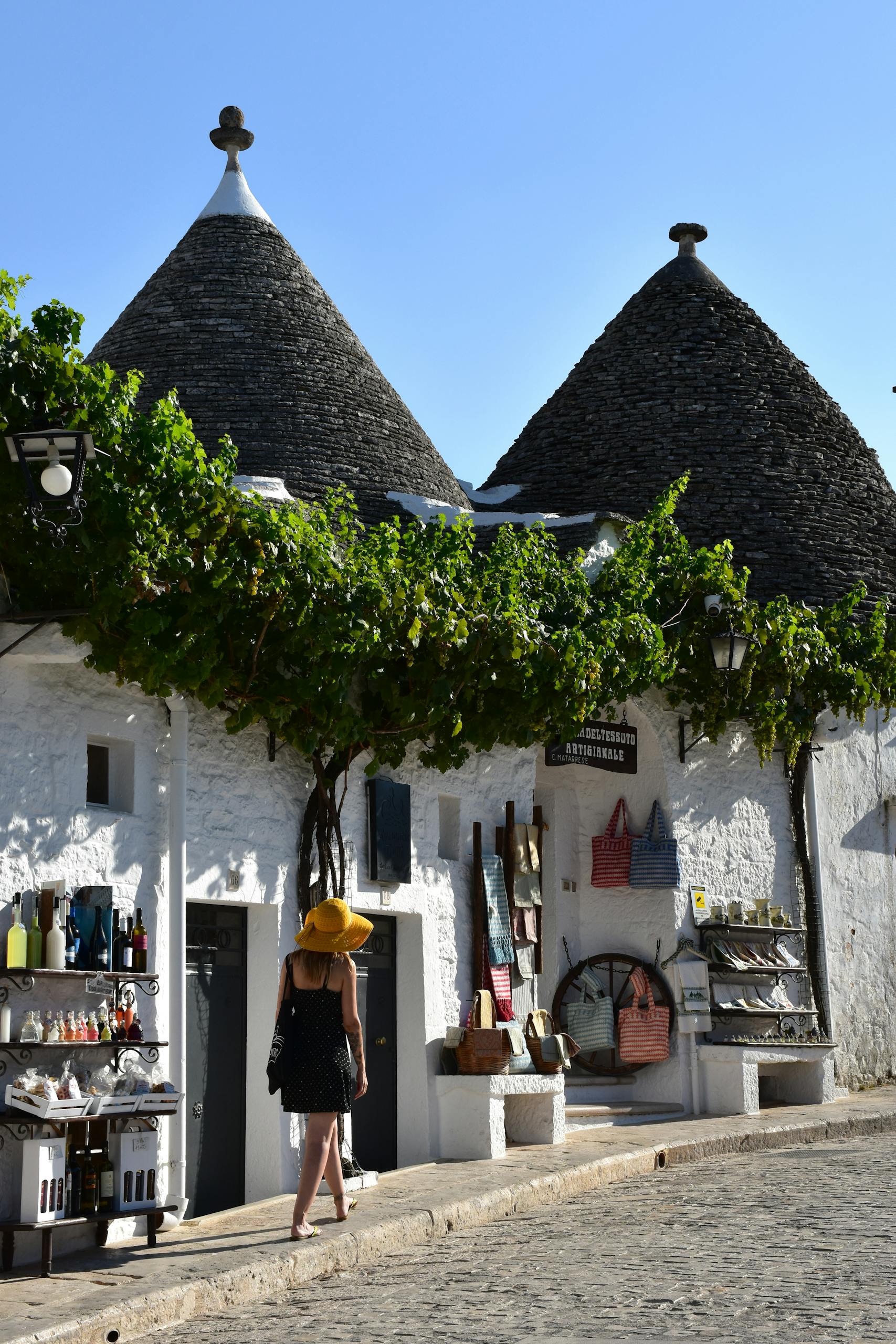Charming view of historic Trulli houses in Alberobello, Italy, with a tourist exploring.