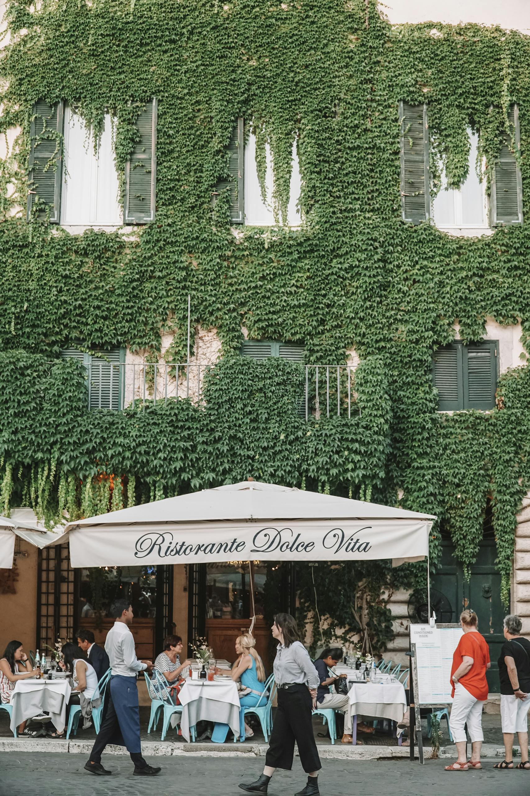 Discover a delightful al fresco dining experience at a Roman restaurant with an ivy-covered facade.