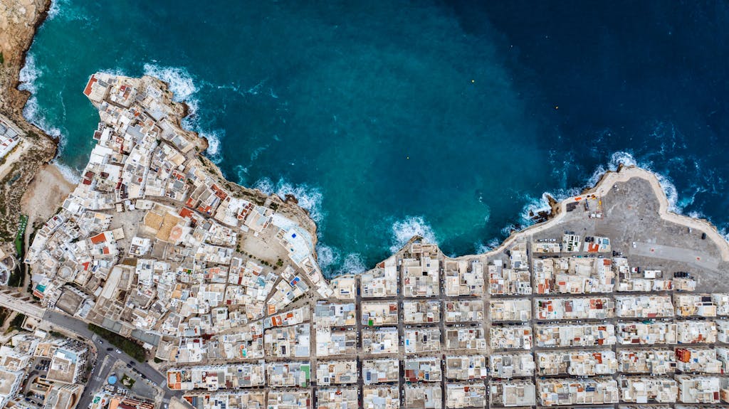 Drone shot of Polignano a Mare showcasing urban coastline against the blue sea.